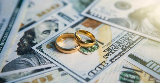 A pile of money with two wedding rings on it