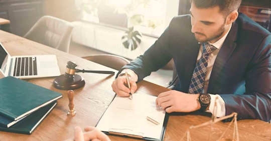 A male attorney sitting at his desk writing something down