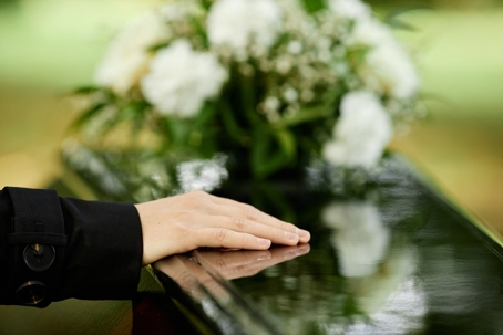 hand on coffin with flowers