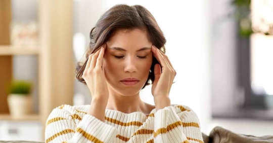 A woman massaging her temples in an attempt at calming her headache