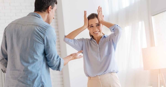 A man and woman arguing. The woman looks distressed and has her hands to her head in frustration.
