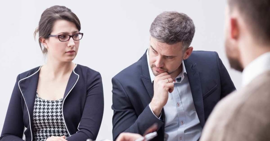 A man and woman appear frustrated at each other as they sit across from another man