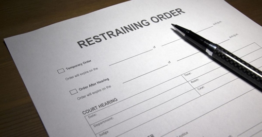 A restraining order form with a pen resting on it