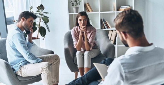 A man and woman sitting across from an attorney. The man and woman both appear frustrated as the attorney takes notes