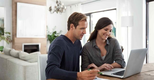 A man and woman sitting at a table looking at something on their computer