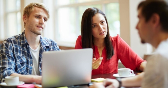 A man and woman sitting across from another man. It seems as if they are working on something or working out something.