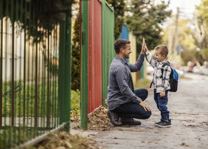 father and son high-fiving outside of school