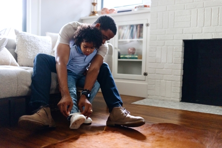 father helping son put on shoes