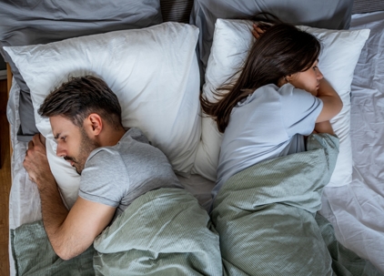 couple in bed facing away from each other