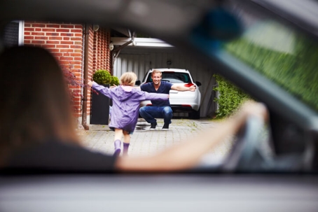 child running up to father while mother watches from car